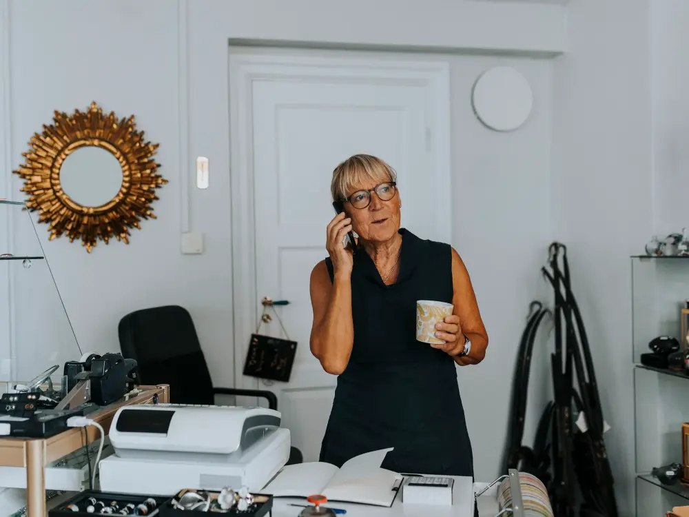 Ältere Dame spricht am Telefon und hält eine Tasse