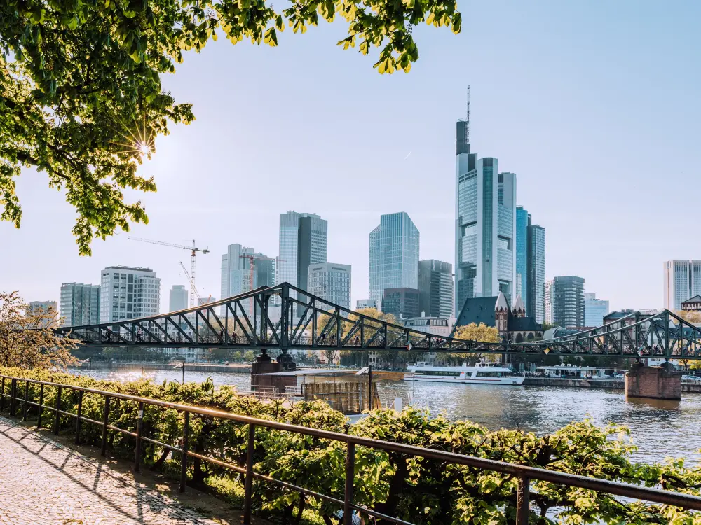 Skyline von Frankfurt mit Eiserner Steg und Mainufer im Sonnenschein