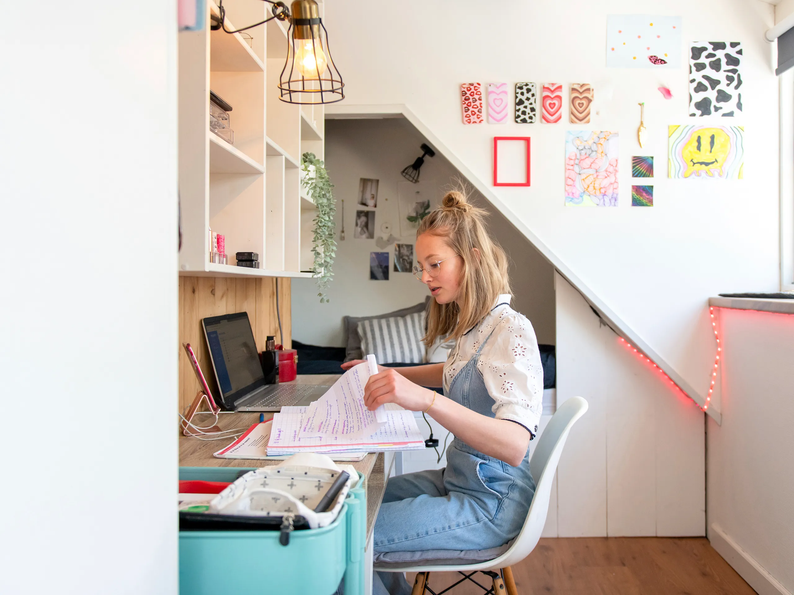 Junge Frau lernt mit Notizen und Laptop in einem kreativen Arbeitszimmer