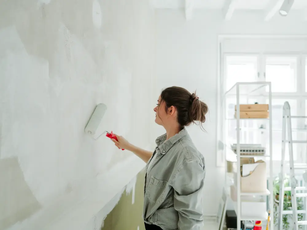 Frau streicht eine Wand mit einer Farbrolle in einem hellen Raum