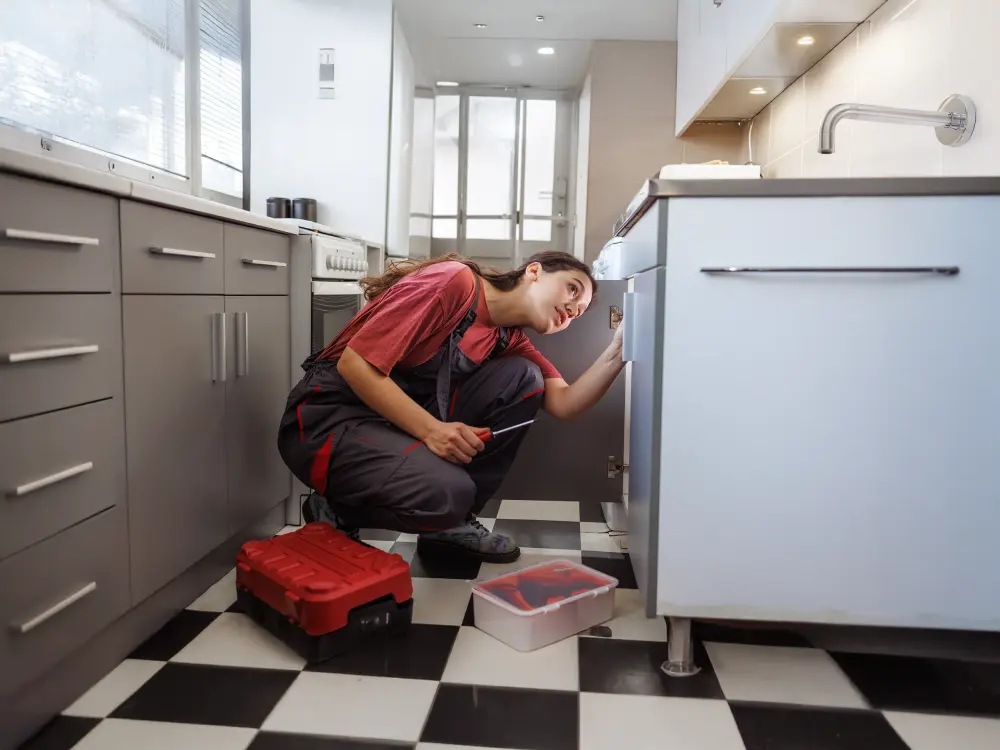 Handwerkerin repariert konzentriert eine Spüle in moderner Küche