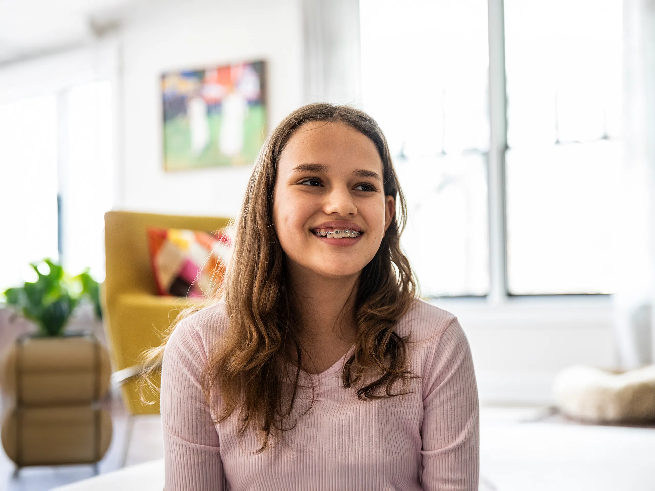 Lachendes Mädchen mit Zahnspange in hellem Wohnzimmer