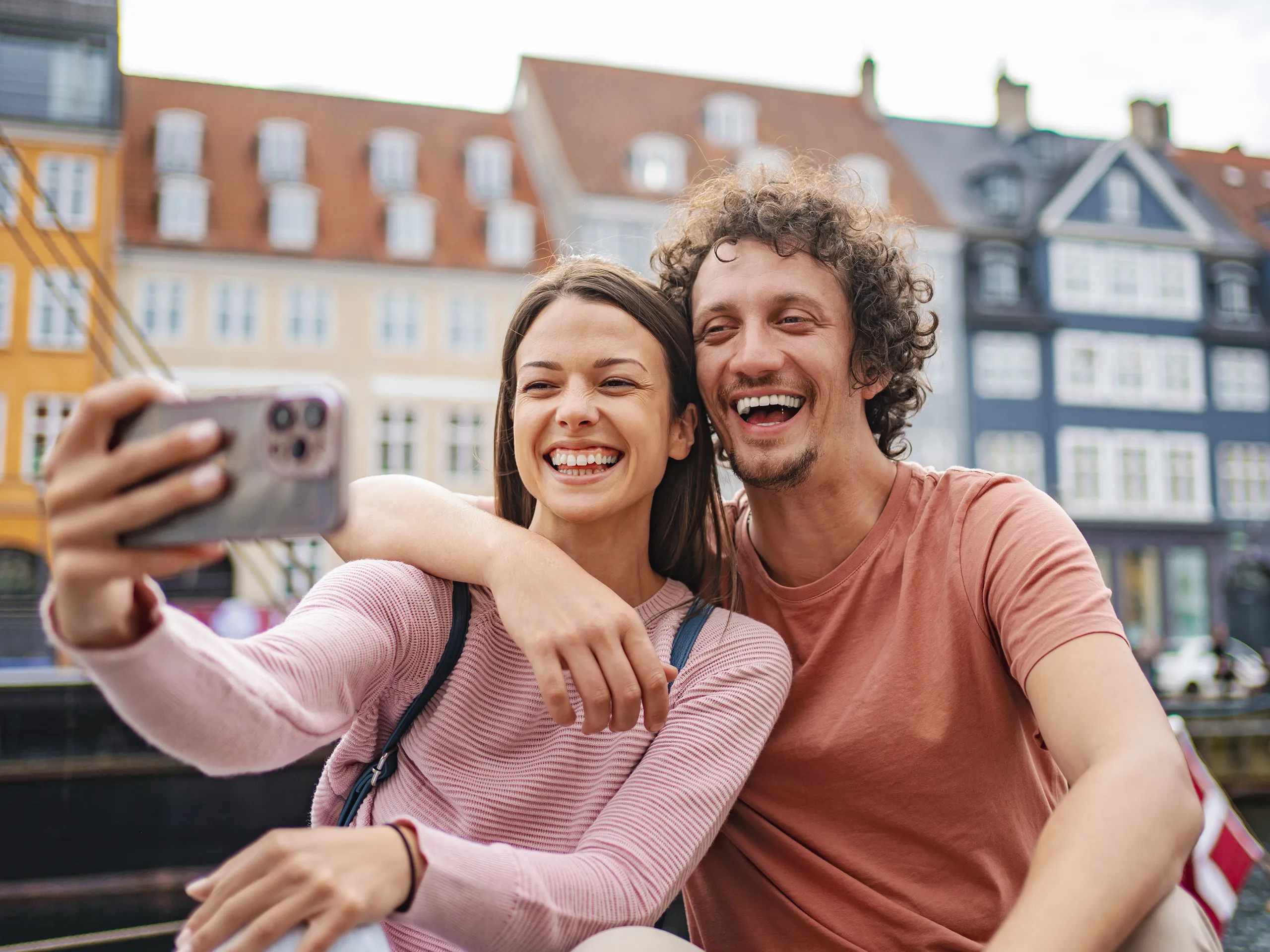 Lachendes Paar macht Selfie vor Altbauten
