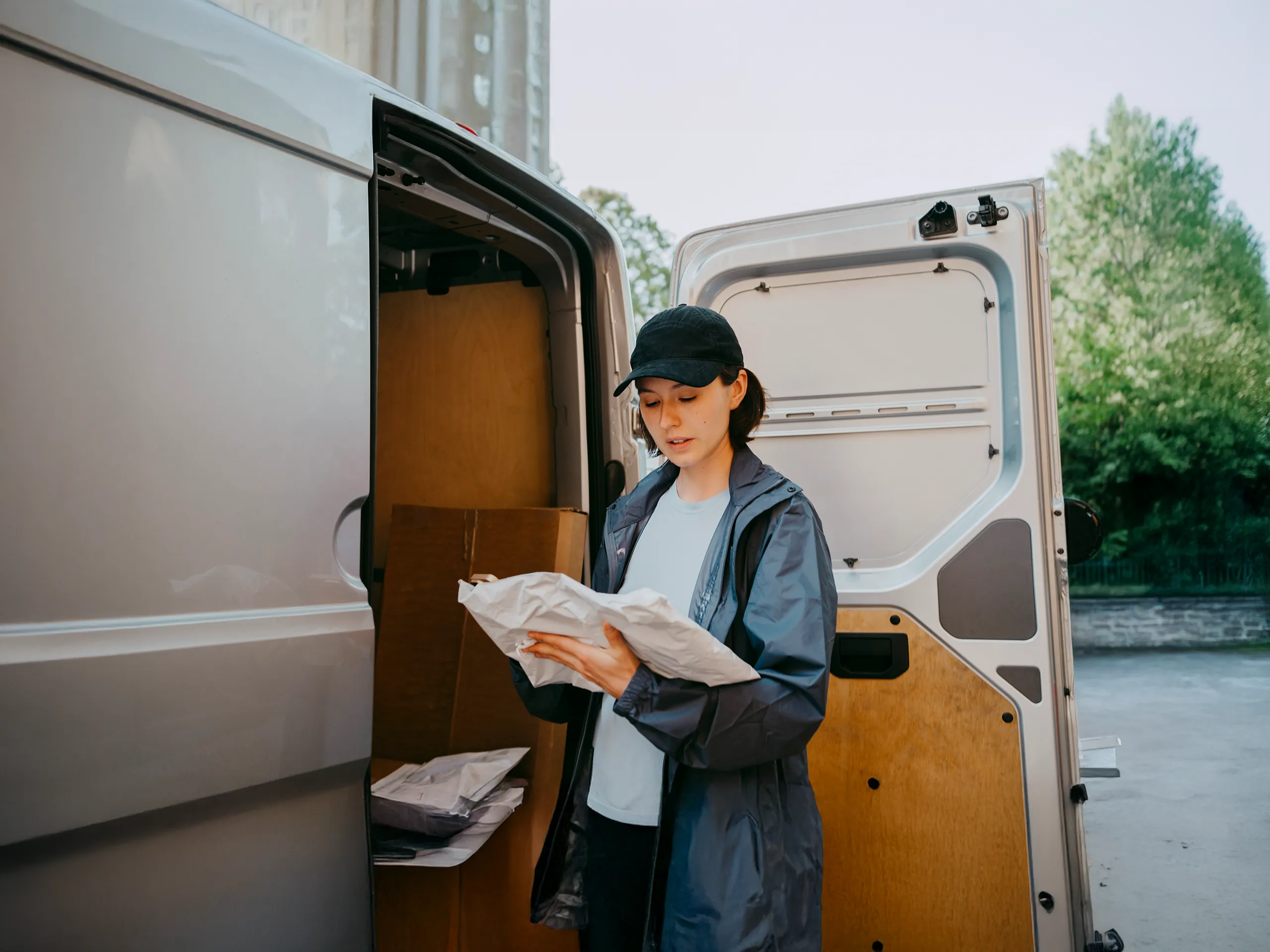 Paketzustellerin überprüft Sendung vor Lieferwagen