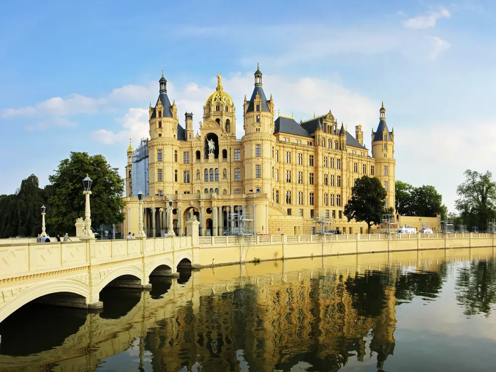Schloss Schwerin mit Brücke und Spiegelung im Wasser bei sonnigem Wetter