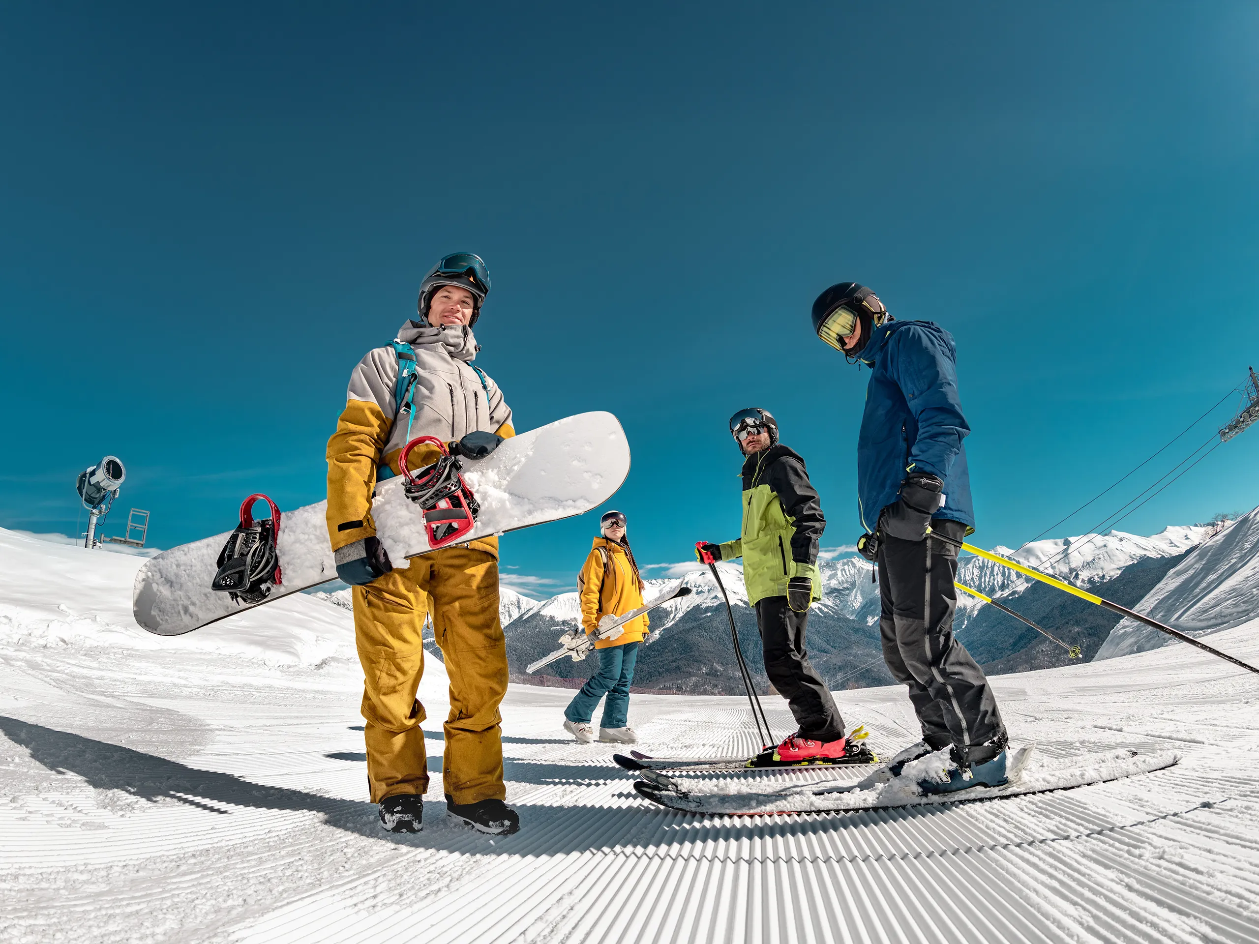 Gruppe von Wintersportlern mit Snowboard und Skiern auf einer verschneiten Piste.