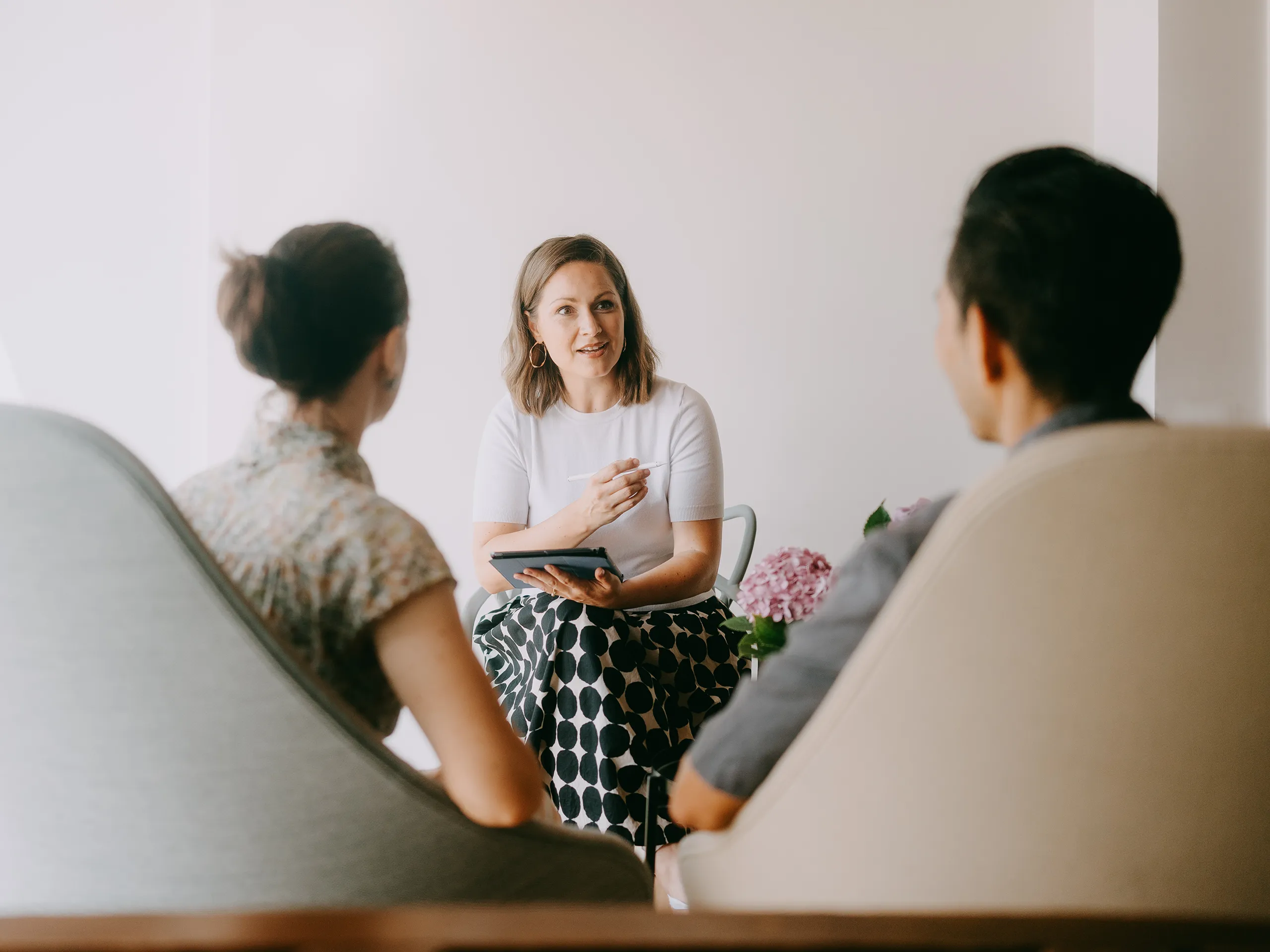 Frau führt ein Gespräch mit zwei Personen in einem hellen Raum.