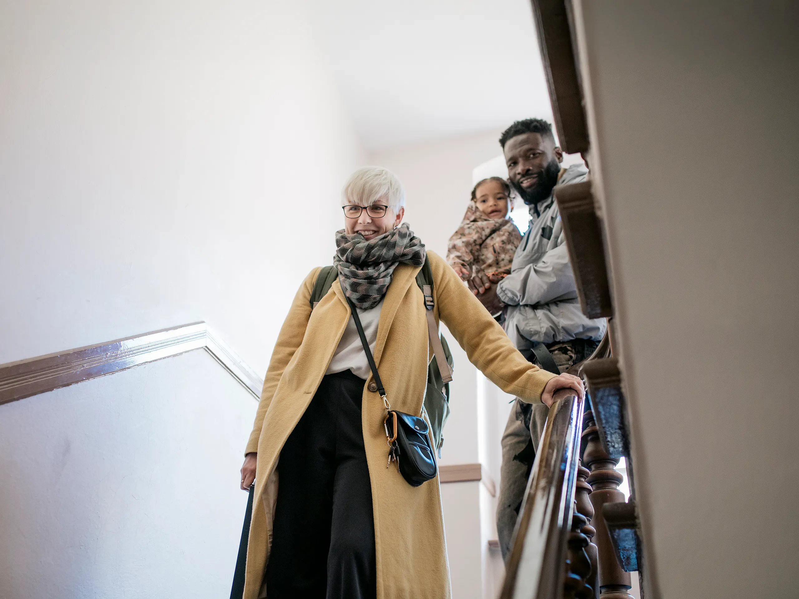 Frau mit Rucksack steigt eine Treppe hinunter, gefolgt von einem Mann mit Kind