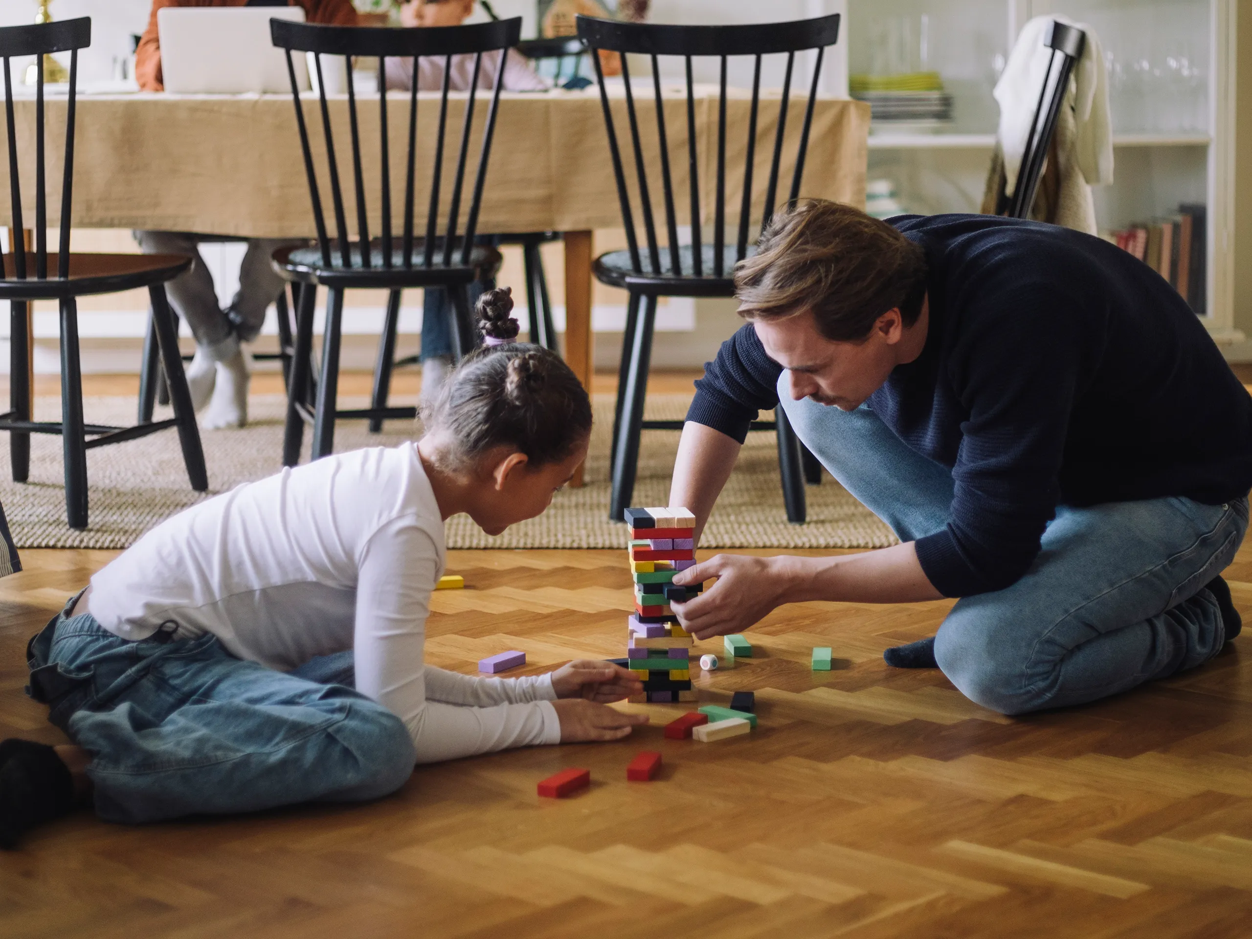 Vater und Tochter spielen mit bunten Bausteinen auf dem Boden